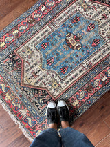 a vintage malayer rug with a neutral field, electric blue medallion and pink and lemon yellow accents