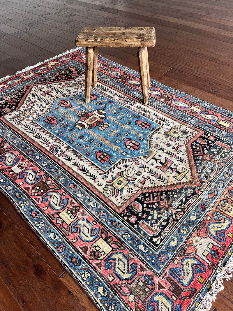 a vintage malayer rug with a neutral field, electric blue medallion and pink and lemon yellow accents