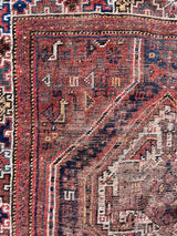 a small vintage shiraz rug with a warm brown, red and coral palette