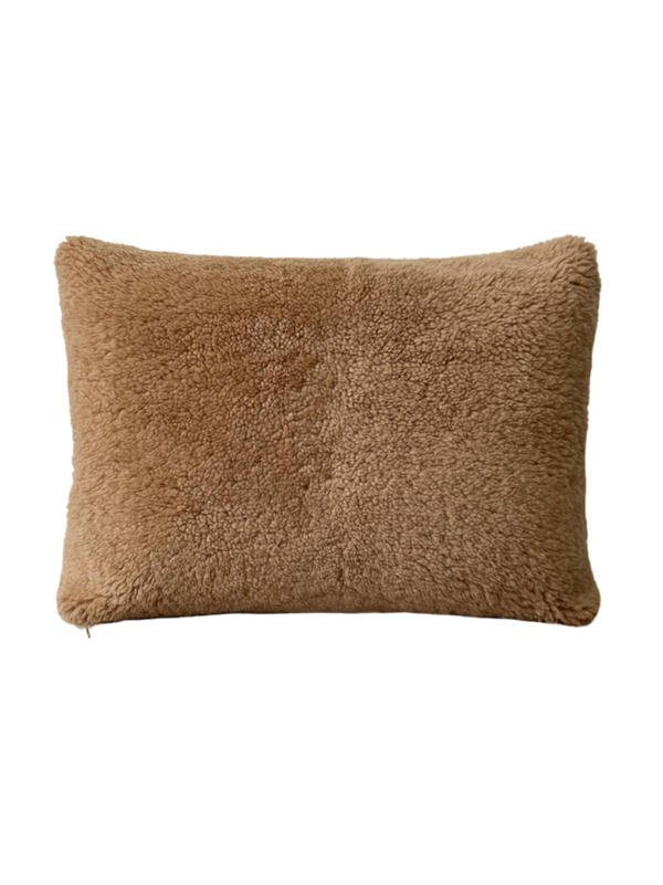a shearling pillow in camel with a velvet backing and exposed brass zipper