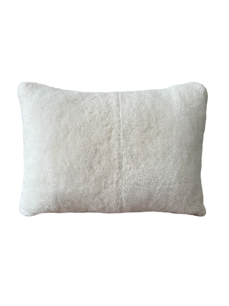a cream lumbar pillow in white shearling