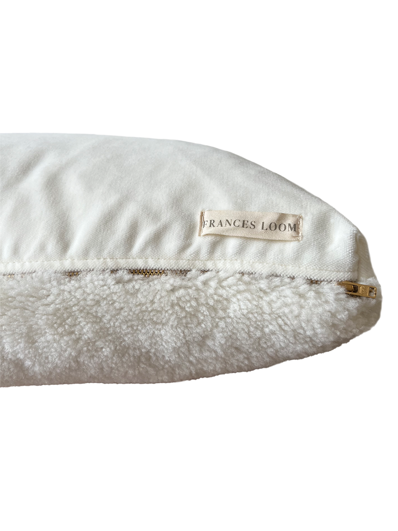 a cream lumbar pillow in shearling, backed with plush velvet with a brass zipper
