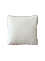 a white shearling pillow backed in plush velvet, with an exposed brass zipper