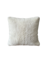 a white shearling pillow backed in plush velvet, with an exposed brass zipper