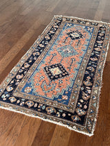 an antique heriz rug with a coral field, dark blue medallions and dark lighter blue accents