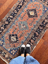 an antique heriz rug with a coral field, dark blue medallions and dark lighter blue accents