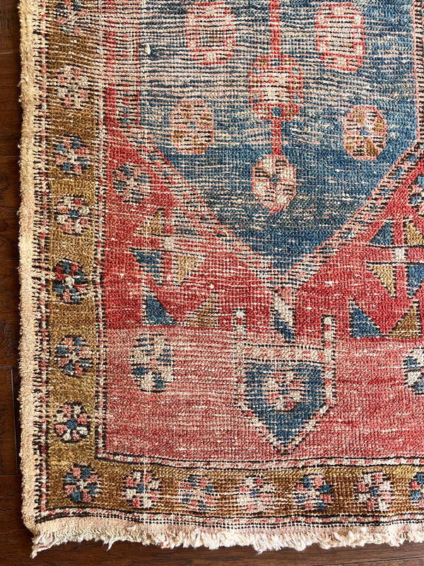 an antique heriz runner with a red and coral toned field and blue medallions
