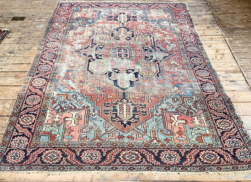 a large antique heriz heritage rug with a faded coral field and a large dark blue medallion