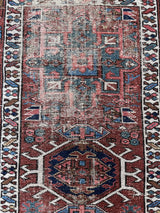 an antique heriz karajah runner with a brick red field with green and blue medallions