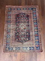 an antique afshar rug with a midnight blue medallion, intricate floral pattern and dot details 