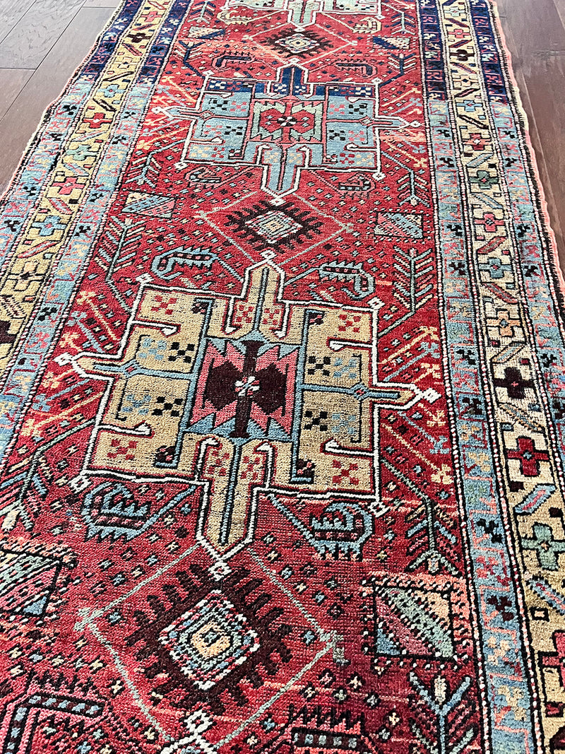 an antique heriz runner with a dark red field and bright turquoise and green medallions