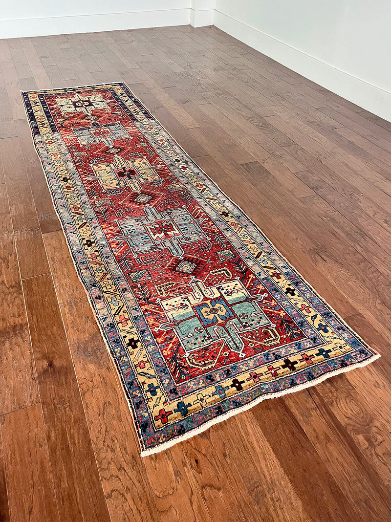 an antique heriz runner with a dark red field and bright turquoise and green medallions