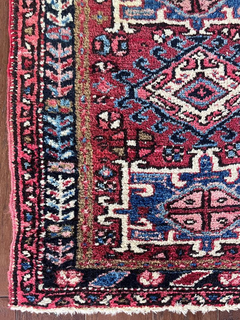 a mini antique heriz rug with a rose pink field and blue medallions