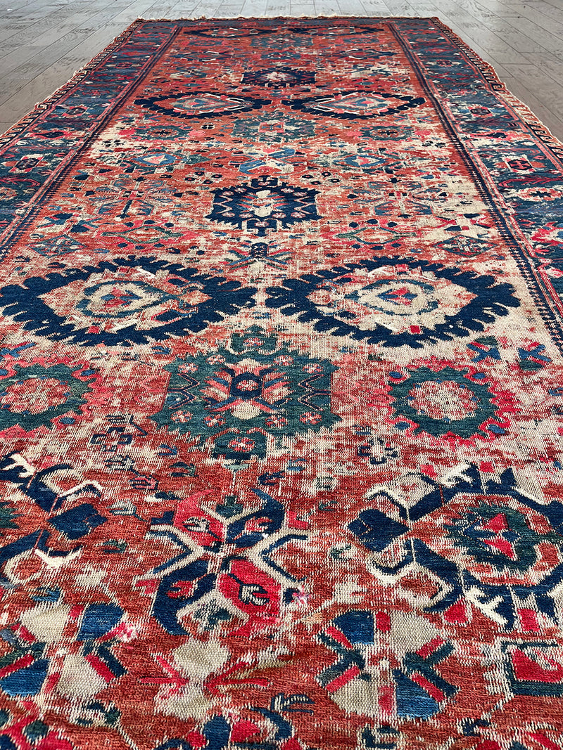 an antique sumac runner with a red field and blue, pink and green accents