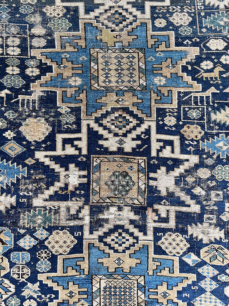 an antique caucasian rug with a blue palette and geometric pattern