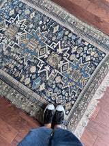 an antique caucasian rug with a blue palette and geometric pattern