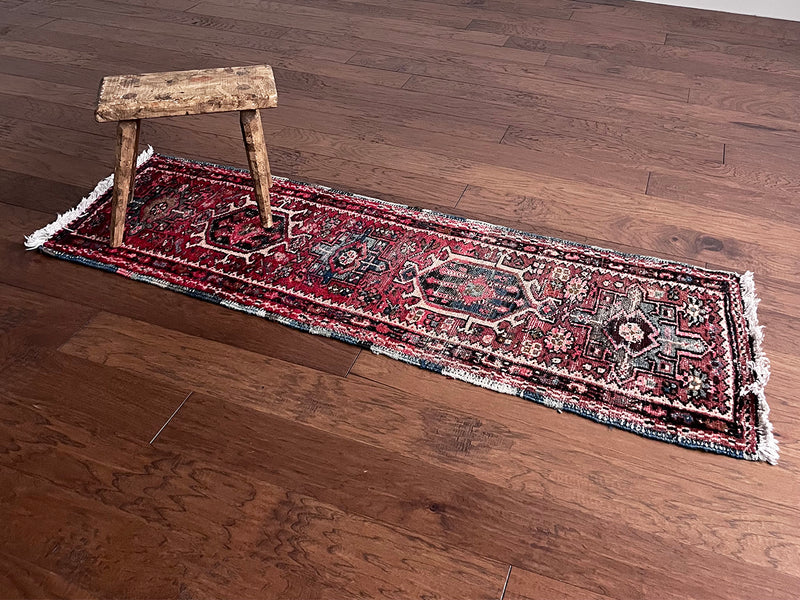 a mini heriz karajah runner with a red and pink field and blue and cream medallions 