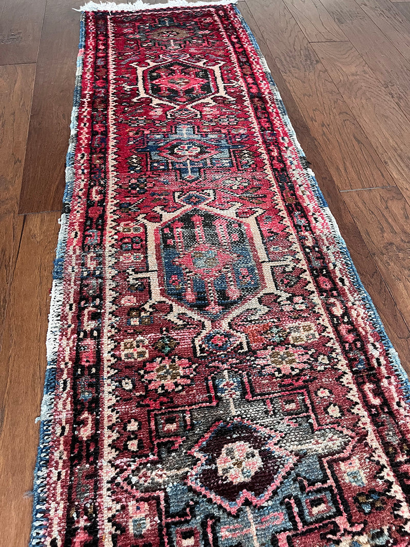 a mini heriz karajah runner with a red and pink field and blue and cream medallions 