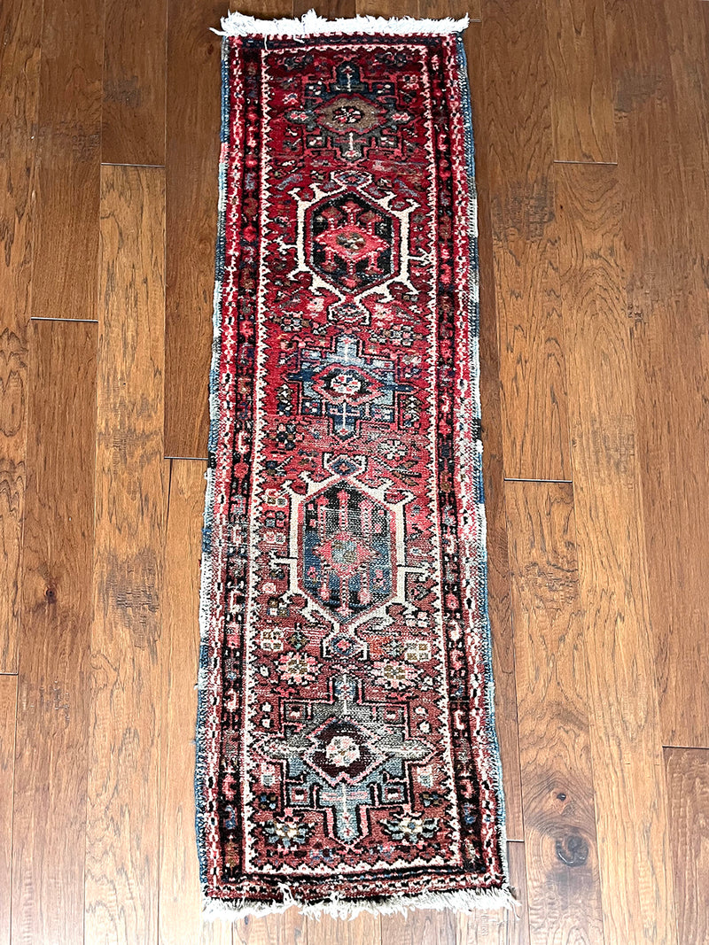 a mini heriz karajah runner with a red and pink field and blue and cream medallions 
