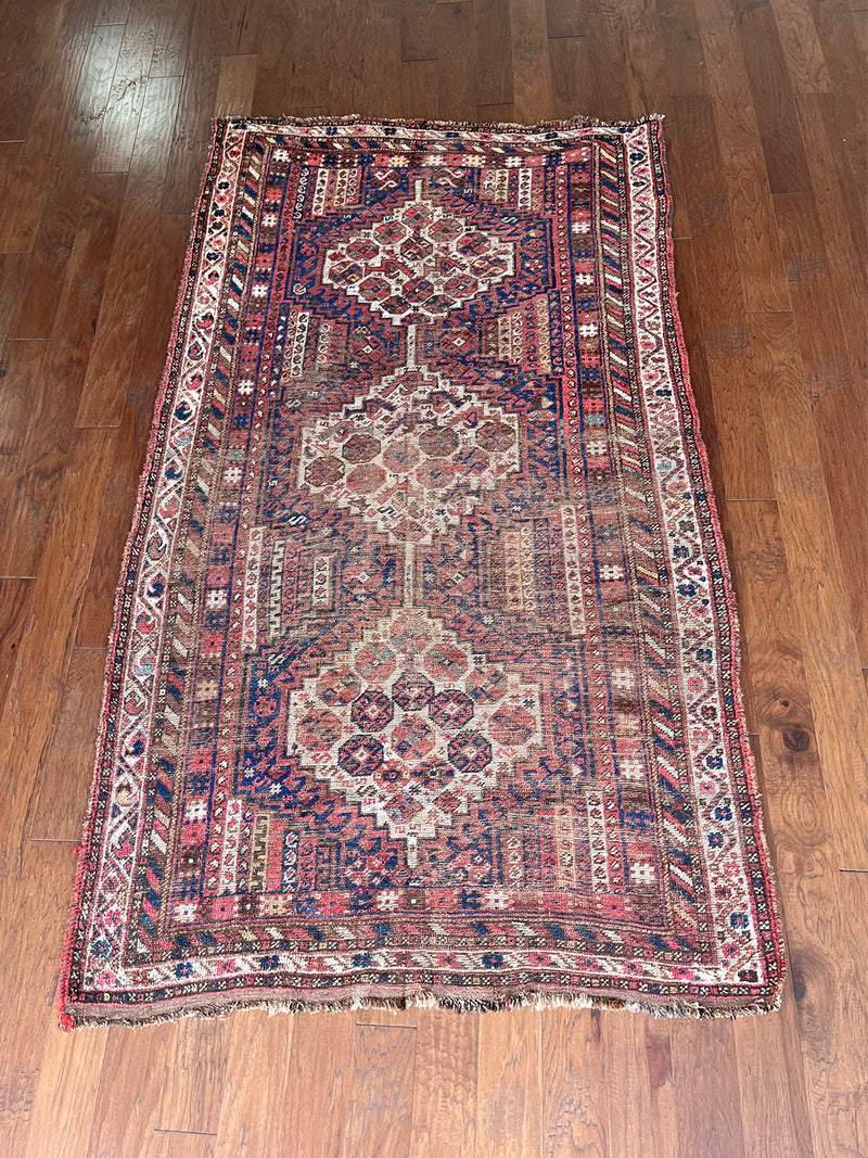 an antique shiraz rug with cream medallions and a delicate stripe pattern