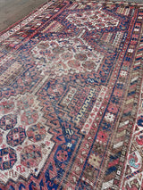 an antique shiraz rug with cream medallions and a delicate stripe pattern
