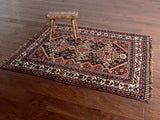 an antique qashqai rug with a black field, brick red and white border