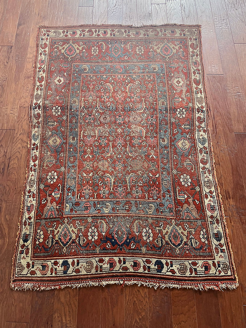 an antique kurdish rug with a brick red field and blue trellis pattern
