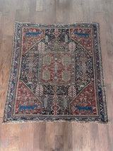 an antique qashqai rug with a dark field and tree of life pattern in brick red 