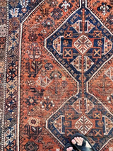a large vintage qashqai rug with a burnt orange field and blue medallions