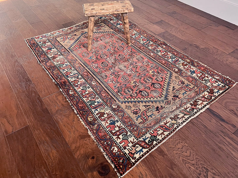 a mini antique malayer rug with a coral field and a pretty floral trellis pattern in blue, yellow and green