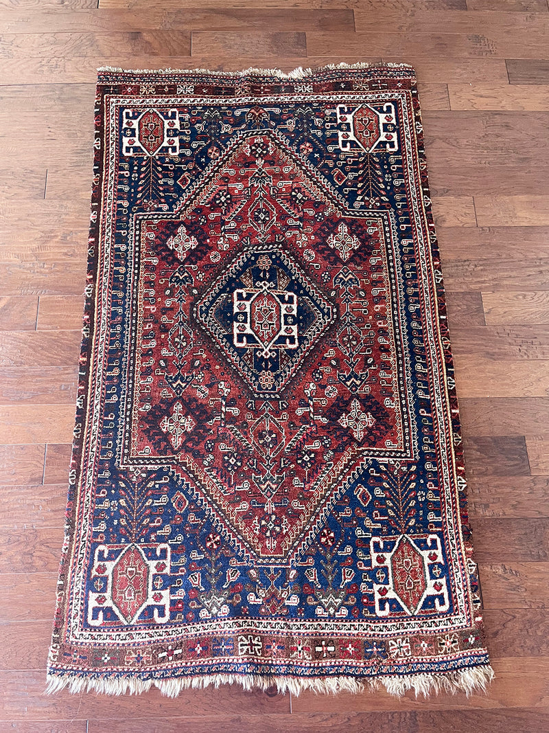 a vintage malayer rug with a dark red field and royal blue corners