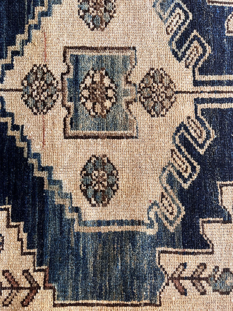 an antique malayer rug with a dark blue field, a large taupe medallion and a lilac border