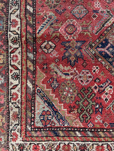 a vintage malayer rug with a raspberry pink field, lilac border and green and blue details