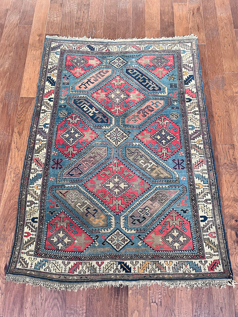an antique kazak rug with a bright blue field and pink, coral and dark blue accents