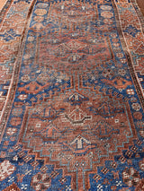 a mini antique qashqai rug with a dark blue field and brick red central medallions