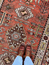 an antique khotan rug with a bright coral field and brown and lemon accents