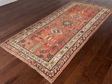 an antique khotan rug with a bright coral field and brown and lemon accents
