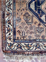a square antique qashqai rug with a blue medallion, coral field and green accents