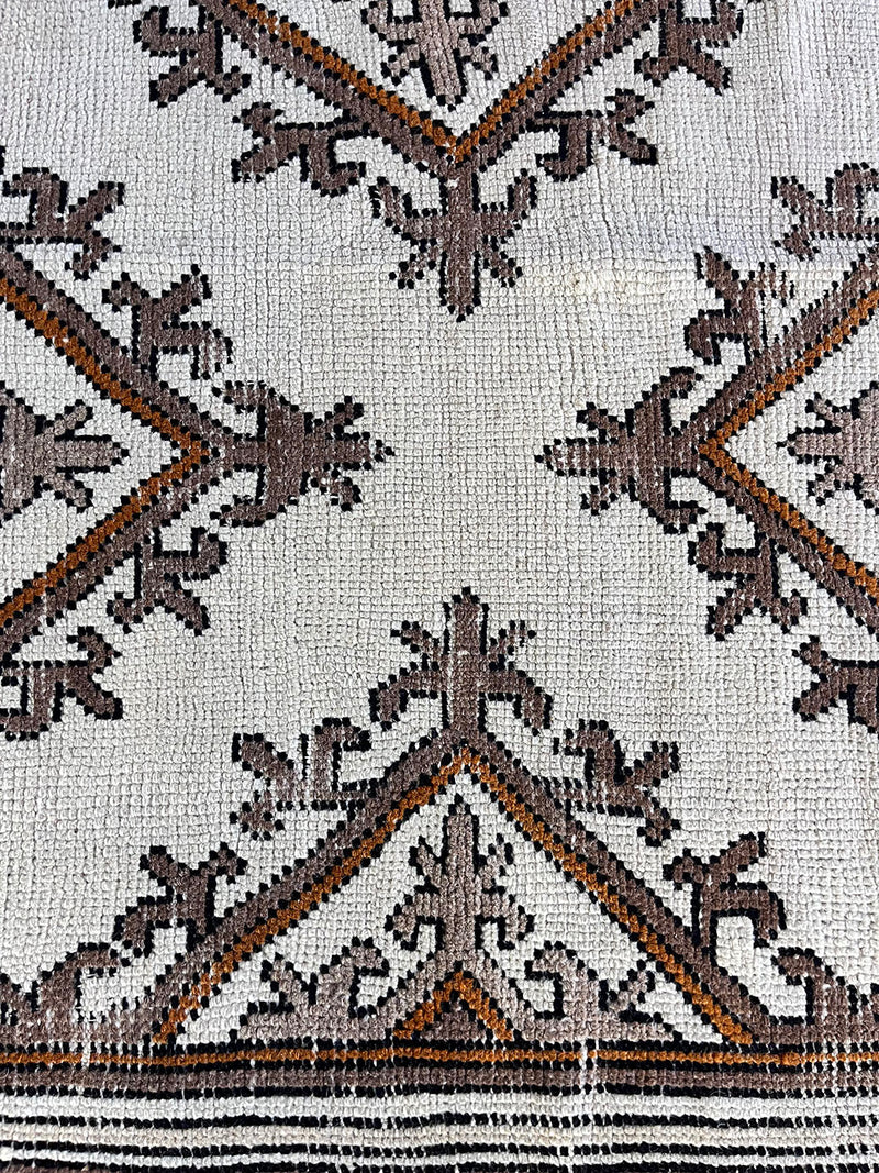 a vintage moroccan rug with a bright cream field and brown, orange and taupe accents