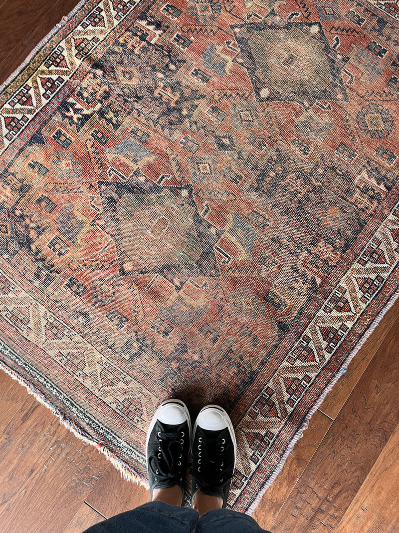 an antique afshar rug with a faded red field and blue medallions