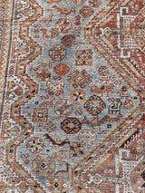 an antique shiraz rug with an icy blue field and coral medallions