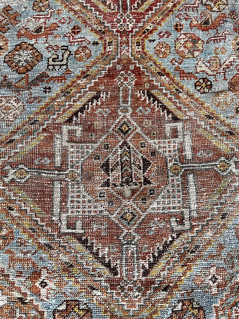 an antique shiraz rug with an icy blue field and coral medallions