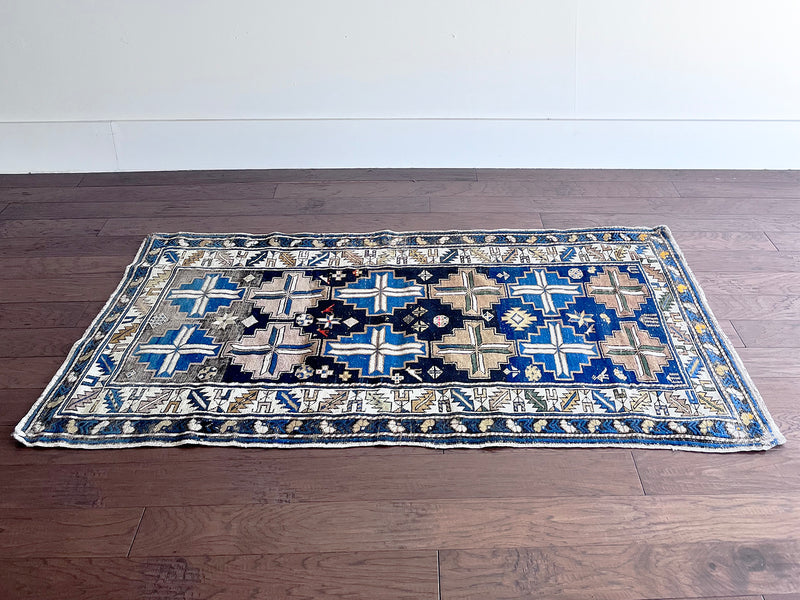 an antique caucasian rug with a blue, brown and taupe pattern