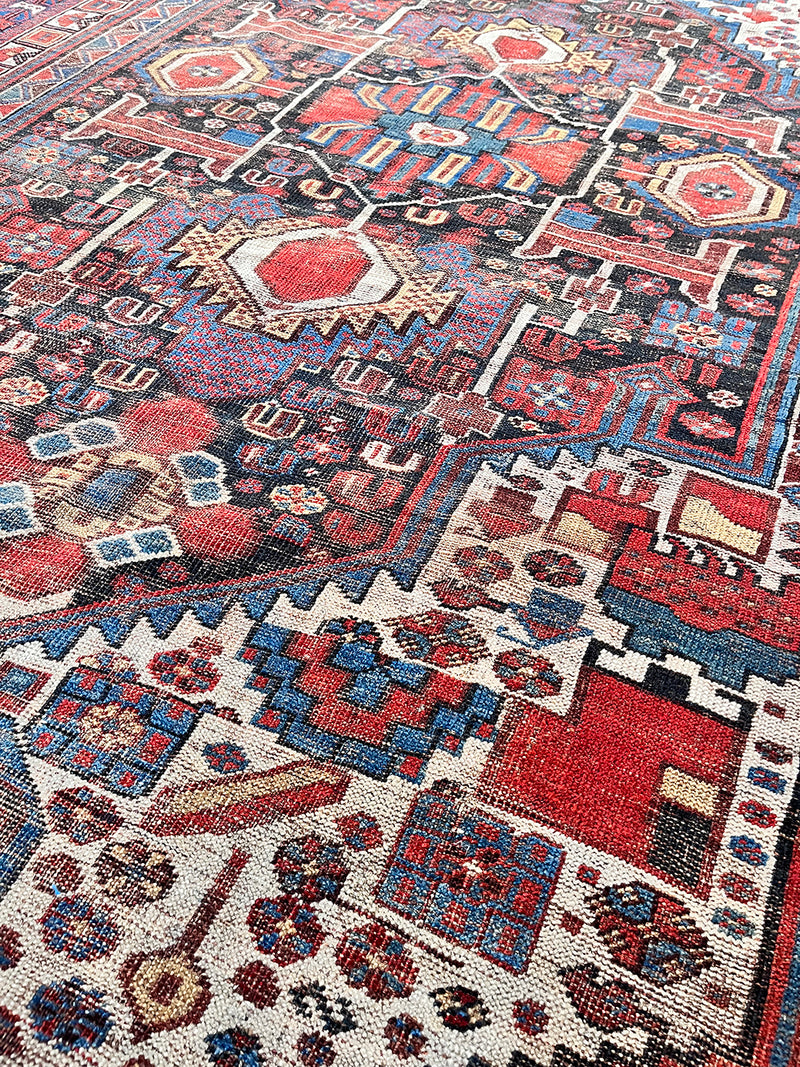 an antique qashqai rug with dark aubergine accents with cream, red and royal blue