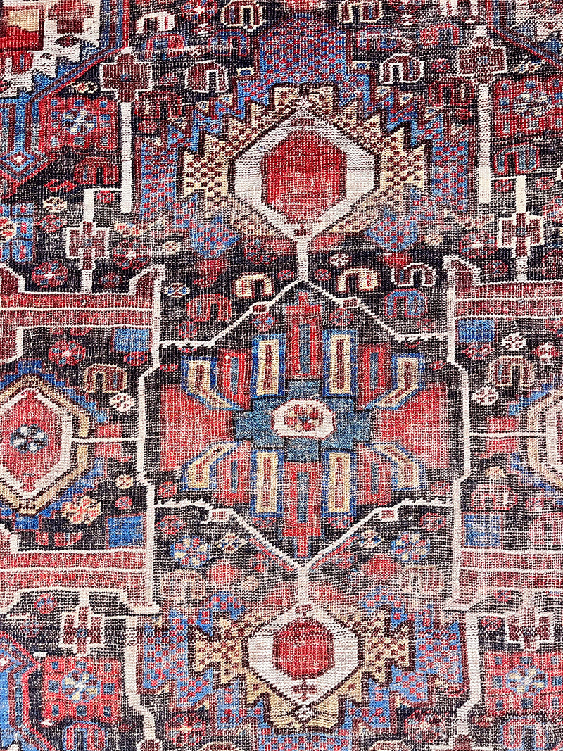 an antique qashqai rug with dark aubergine accents with cream, red and royal blue