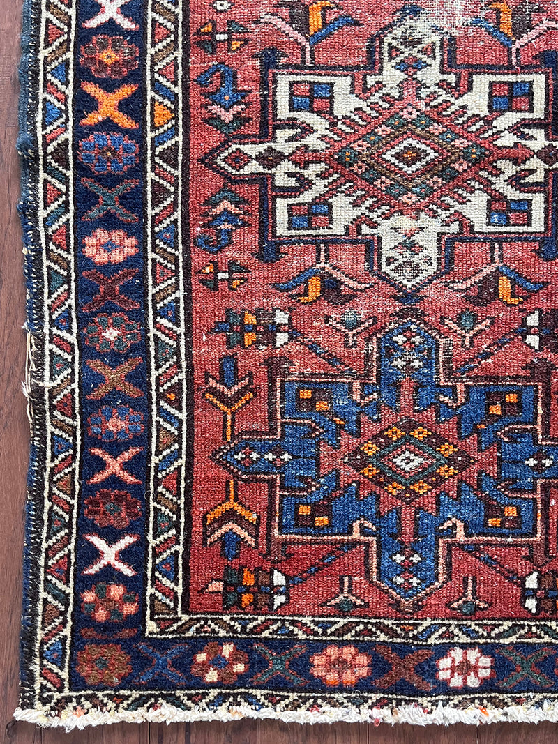 a mini vintage heriz karajah rug with a coral field and blue and white medallions