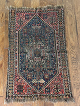 a mini antique qashqai rug with a midnight blue field and neon pink accents