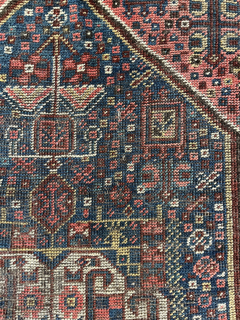 a mini antique qashqai rug with a midnight blue field and neon pink accents