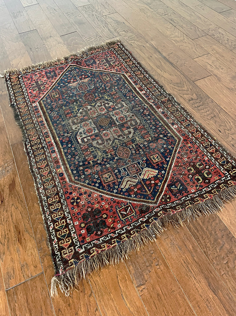 a mini antique qashqai rug with a midnight blue field and neon pink accents