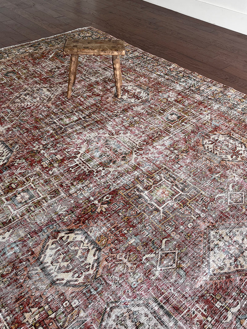 an antique heriz karajah rug with a dark red field and teal blue medallions